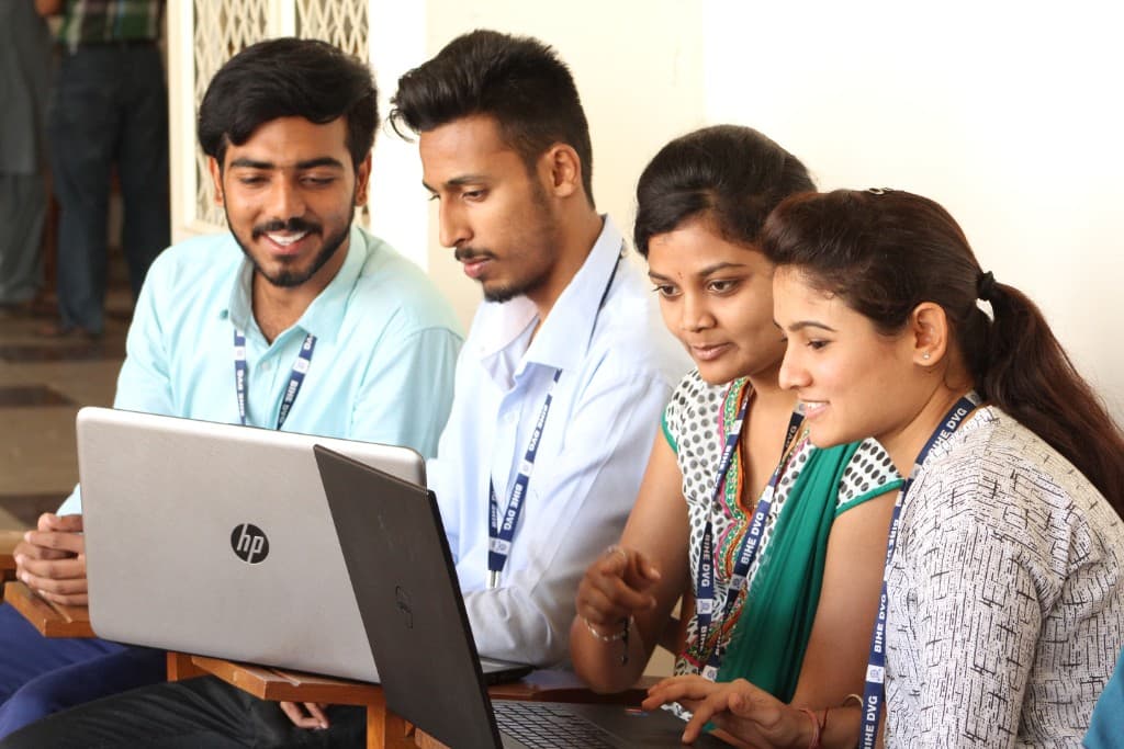 B.Com students collaborating with laptops at BIHE Davangere