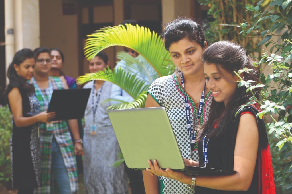 B.Com students collaborating with a laptop at BIHE Davangere
